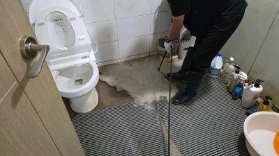 욕실 바닥 배수 입구에서 장비를 다루는 작업