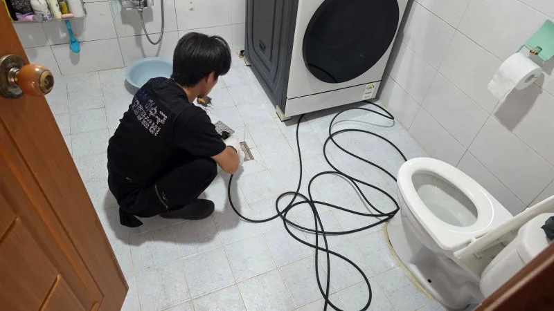 부평동 주택 욕실 배수구 주변을 살피는 작업자 뒷모습