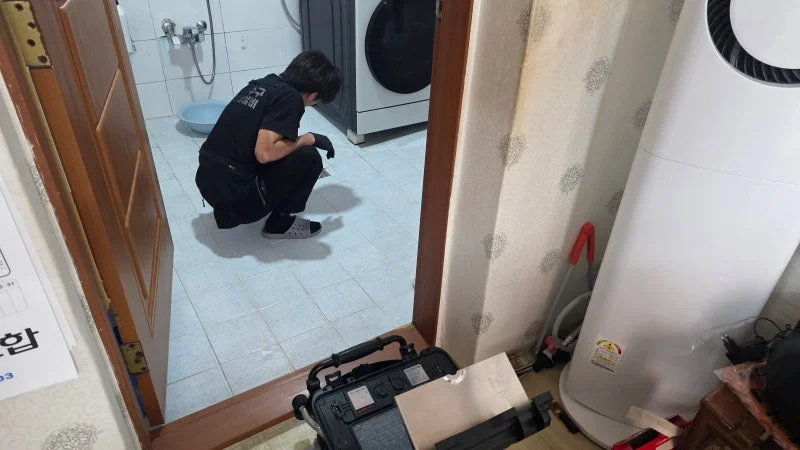 부평동 주택 욕실에서 배수구와 장비를 확인하는 모습