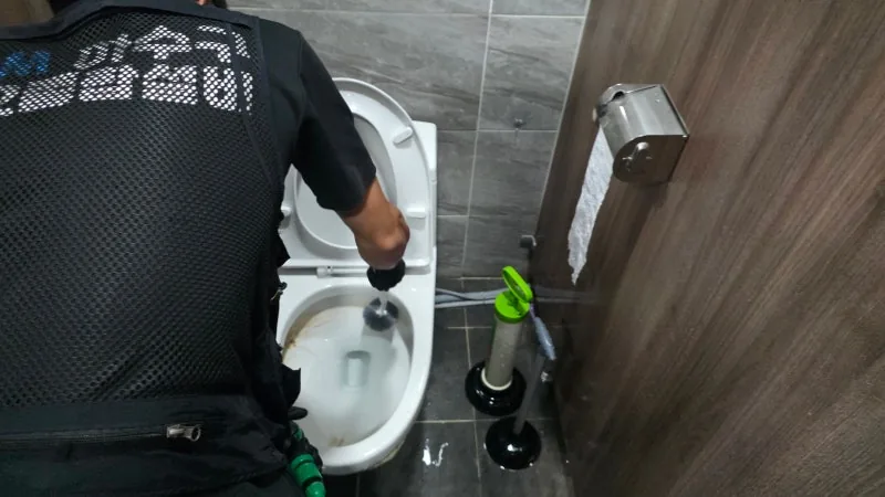 변기 배수 구간에 전용 관통 장비를 적용하는 작업 장면